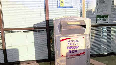 gen z young man votes by dropping mail-in ballot letter in slot at voting booth with offical ballot drop box sign for democratic government election in presidential race