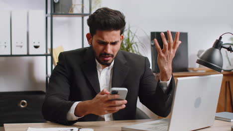 indian office business man use smartphone surprised by bad news, fortune loss, fail, lottery results