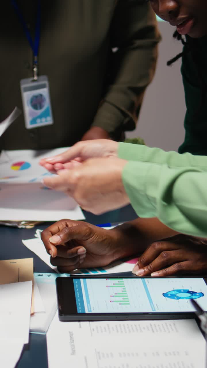 Vertical Video Diverse team members meeting after hours to share data reports