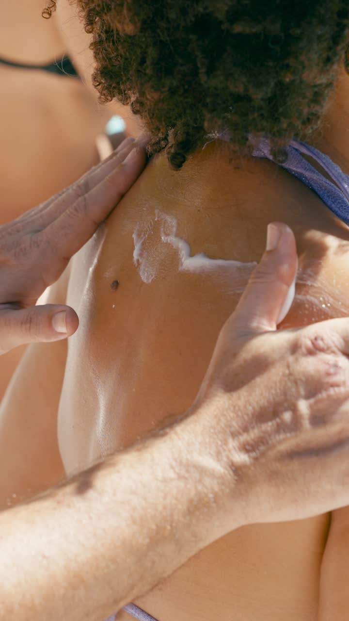 Close-up of Hands Applying Sunscreen to a Person's Shoulder