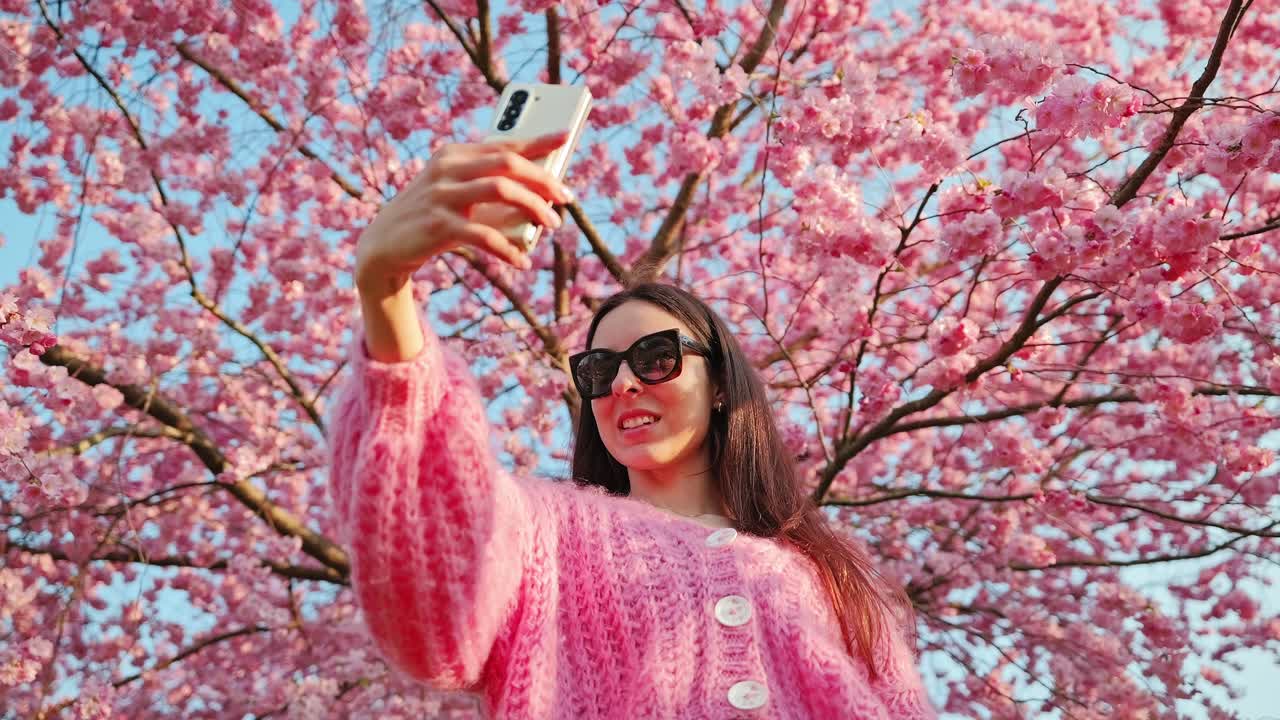 Joyful moment of traveler capturing spring memories among pink cherry flowers