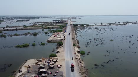 luftaufnahme der straße, umgeben von überschwemmter landschaft auf beiden seiten in sindh, pakistan