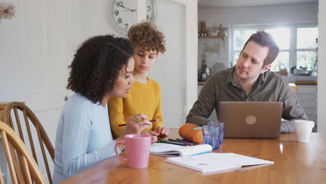 El-Padre-Trabaja-En-La-Computadora-Portátil-Mientras-La-Madre-Ayuda-A-Su-Hijo-Con-La-Tarea-En-La-Mesa-De-La-Cocina.