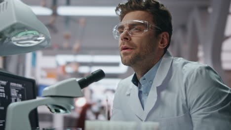 técnico médico examinando el microscopio haciendo una investigación en el laboratorio de cerca.