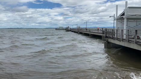 Pan-View-of-Woody-Point-Jetty,-Windy-Day,-Choppy-Ocean