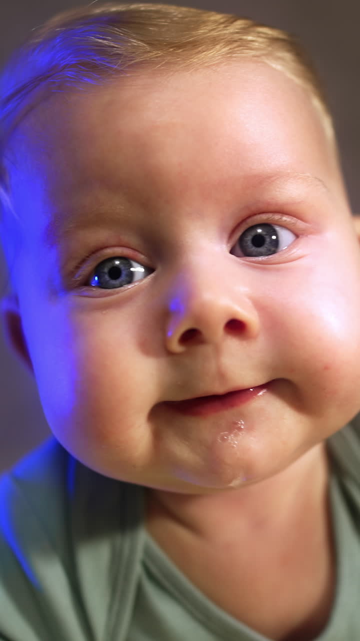 Beautiful Caucasian big-eyed infant. Face of a cute baby looking at camera. Close up. Vertical video