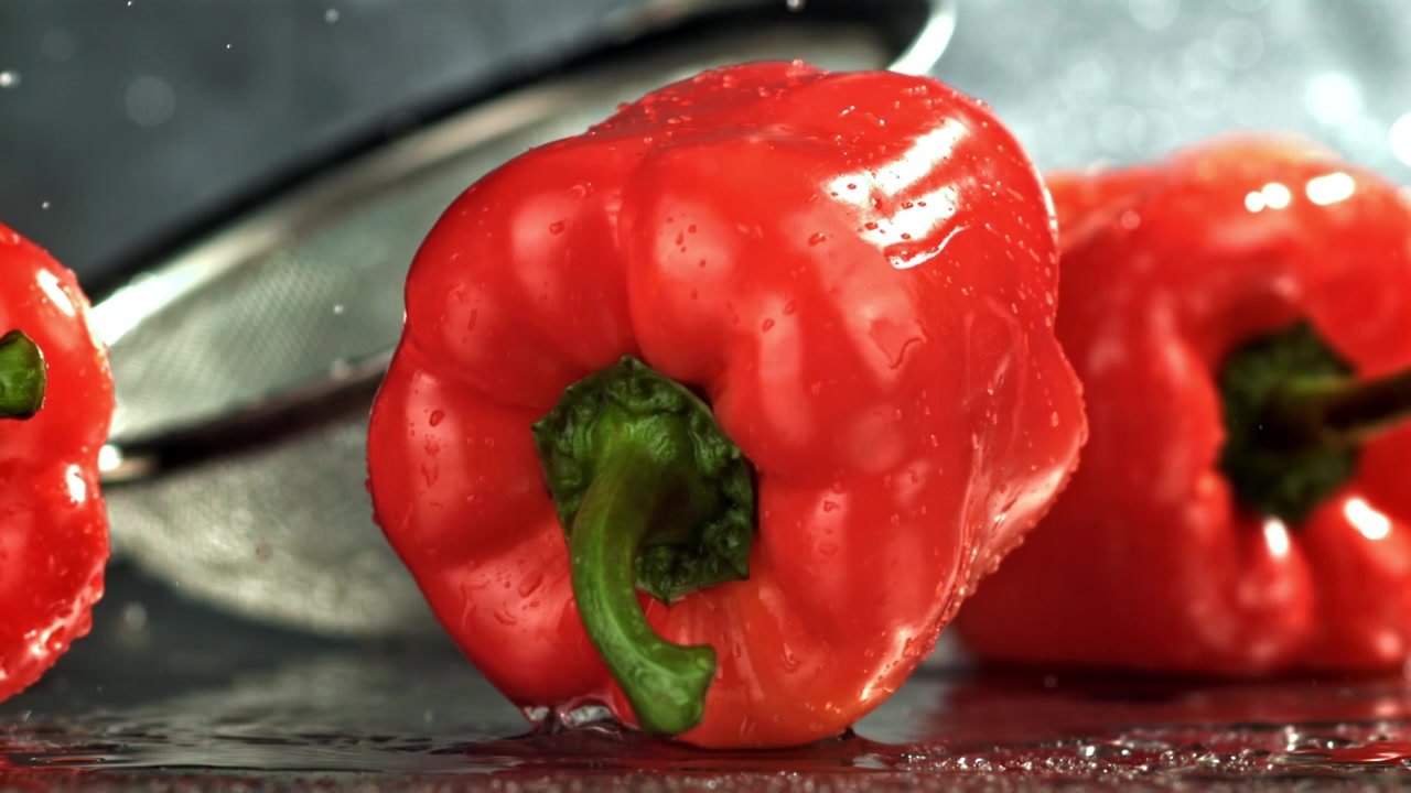 Čerstvá červená paprika padající a stříkající vodu ve zpomaleném záběru