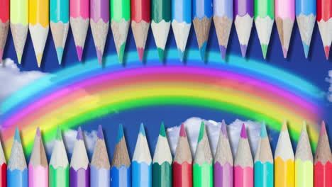 varios lápices de colores contra el arco iris en el cielo azul