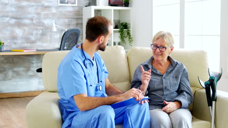 doctor assistant taking notes on clipboard while listening to old retired woman in nursing home