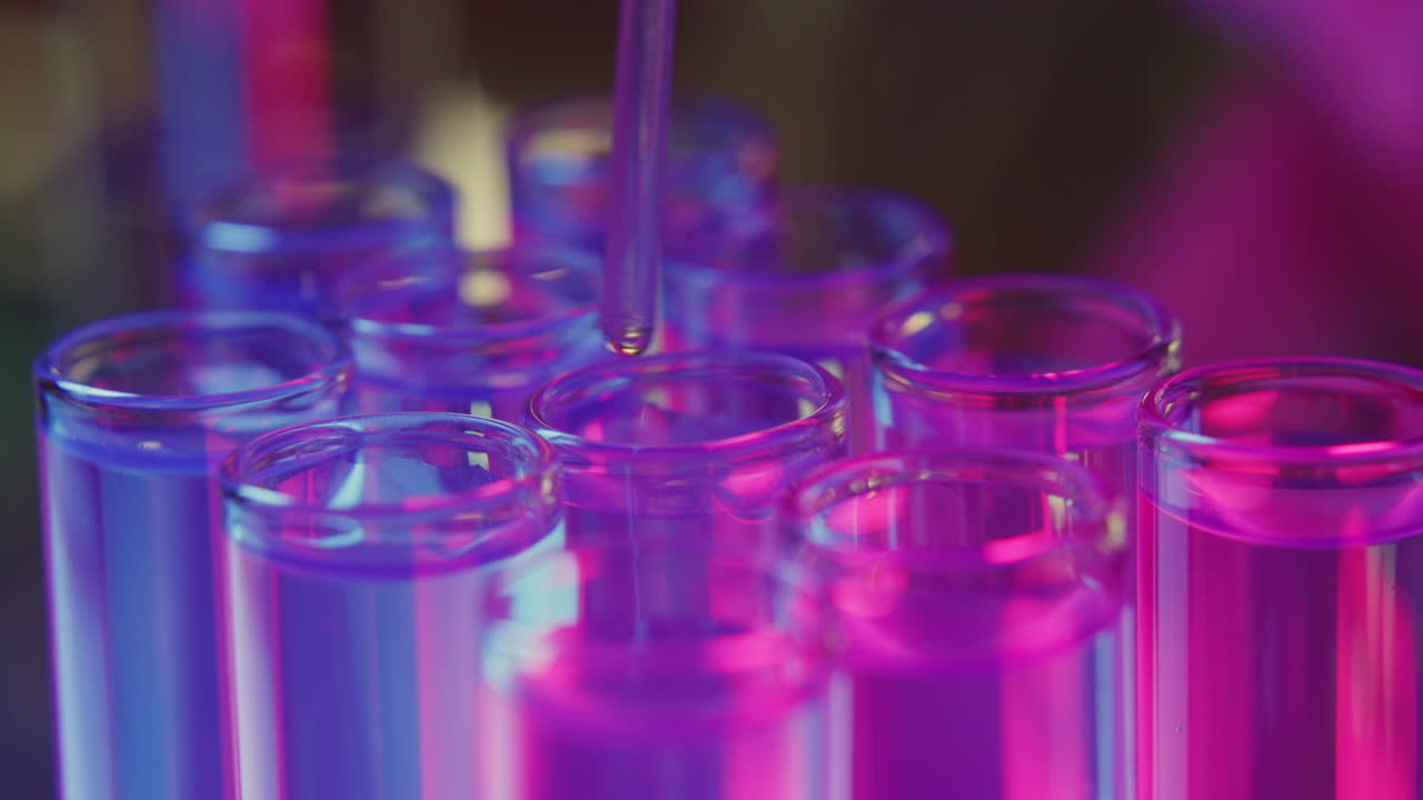 Pipette Dispensing Liquid Chemical into Test Tubes under Neon Illumination