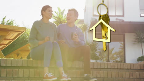 animation of gold house key and key fob over diverse couple drinking tea at new home