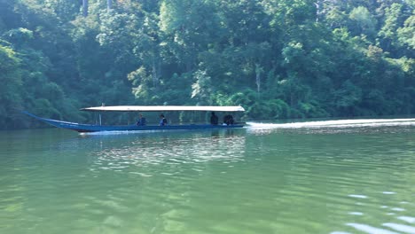 a floating platform moves closer to the forested shoreline.