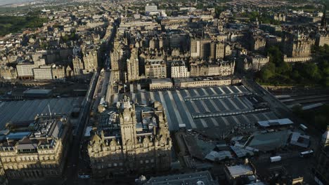 rising aerial view of the balmoral clock tower to reveal how large edinburgh's downtown sector is