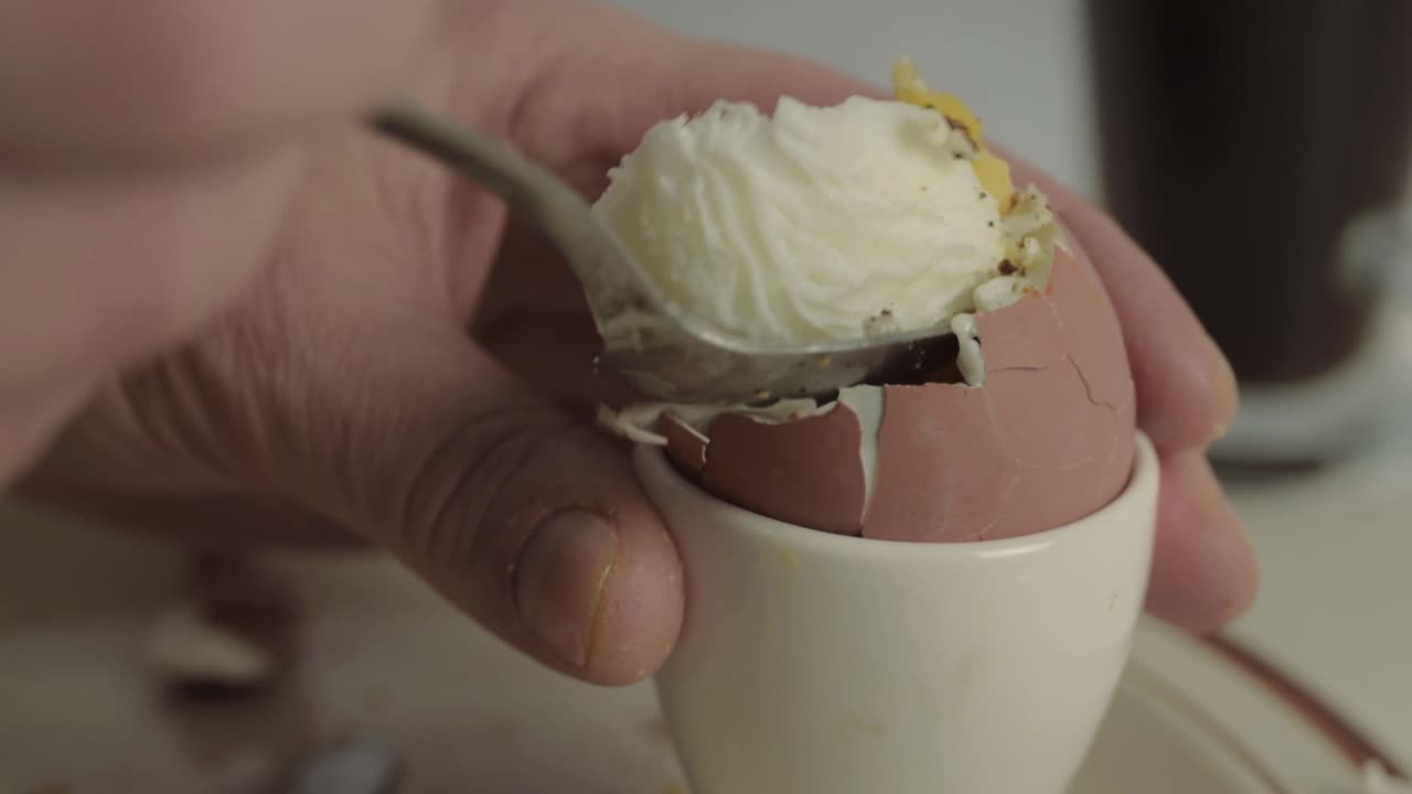 Hand eating boiled egg with spoon close up shot