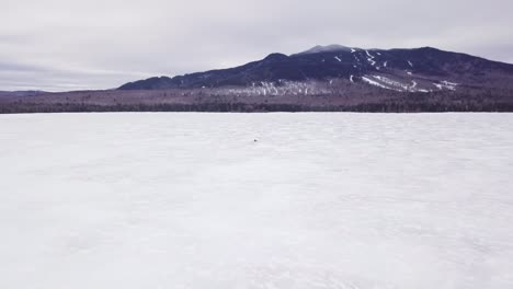 a lone snowmobile treks across the frozen surface of fitzgerald pond, maine