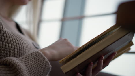 close-up of a hand gently turning to a new page in a book with focus on fingers and book texture, soft background highlighting the peaceful reading experience