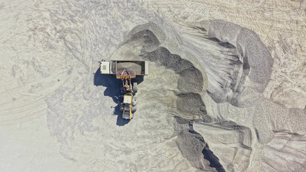 Granite quarry activity with machinery moving and shaping materials in a large open area