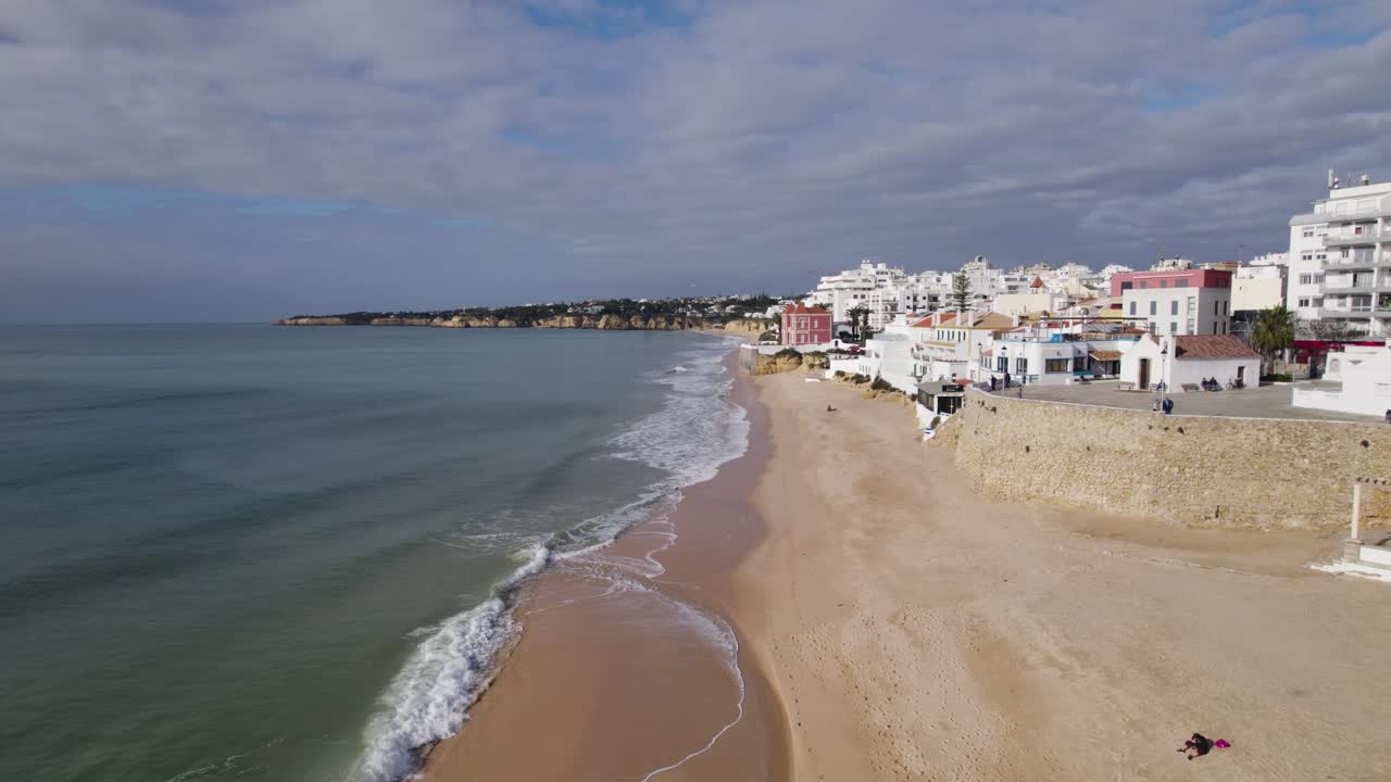 Volo aereo lungo la costa della spiaggia di Armação de Pêra con le onde che si infrangono dolcemente