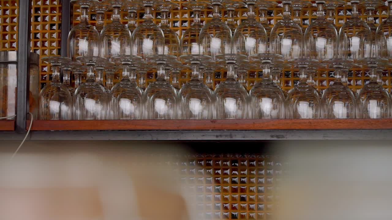 Rows of glass glasses arranged in a row on a wooden shelf