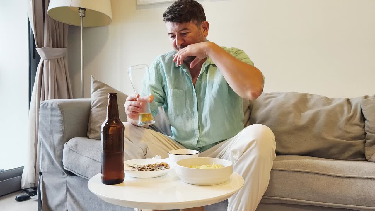 Man drinking and snacking while relaxing on a couch
