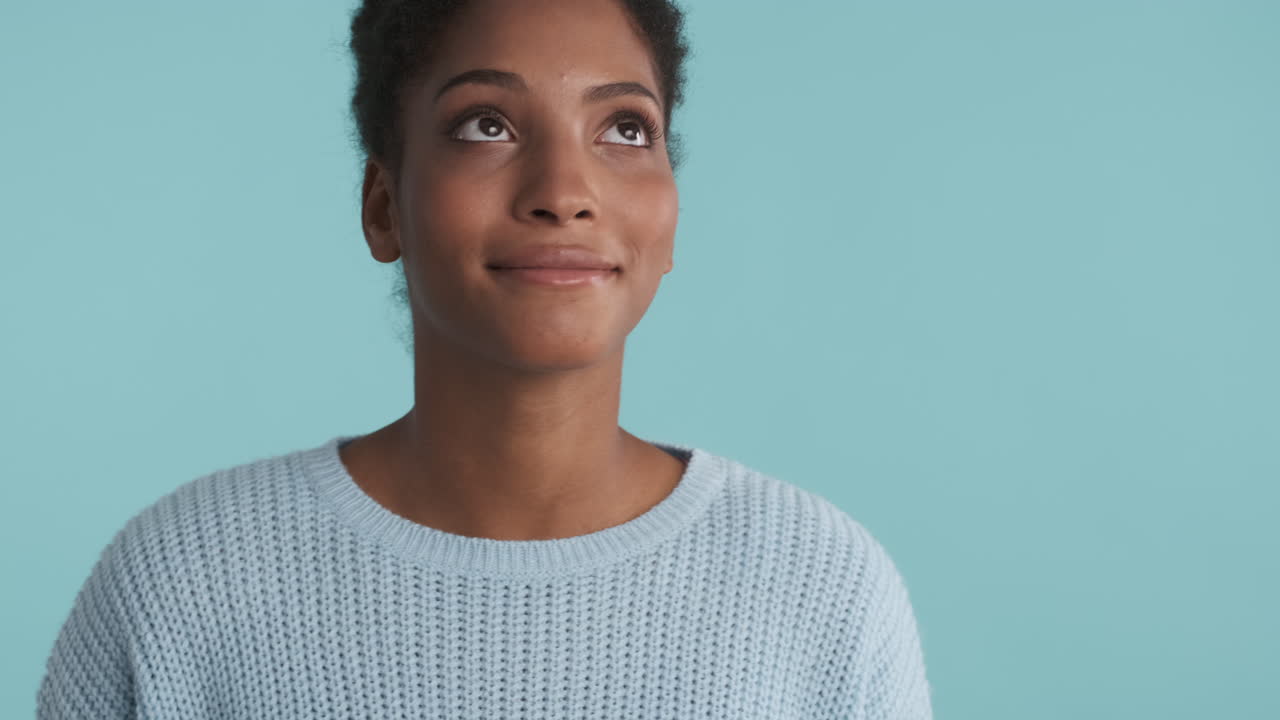 Young woman in blue sweater daydreaming