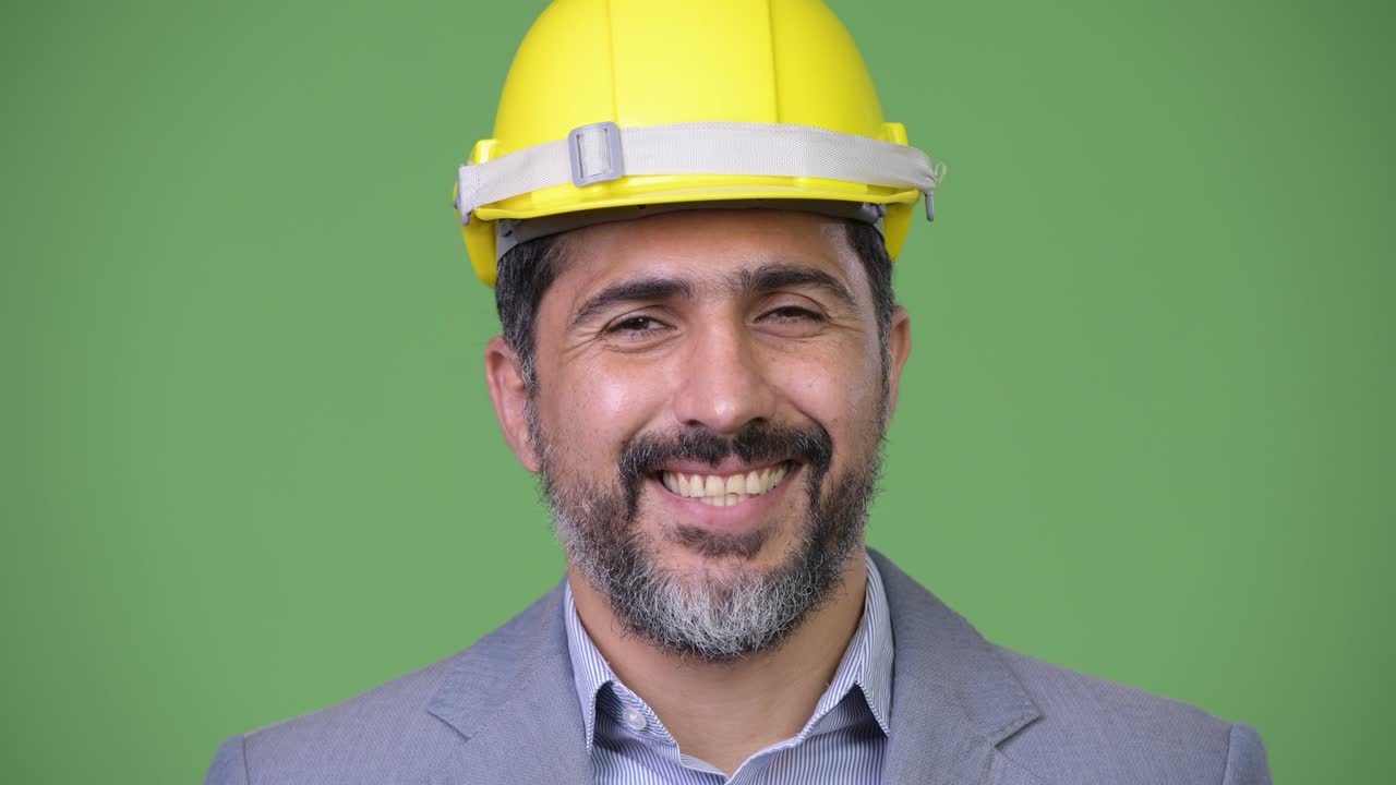 Handsome happy Persian bearded businessman as engineer smiling