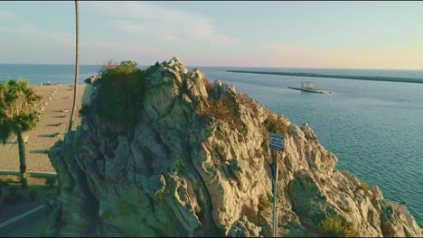 aerial view of a rock by the beach in newport beach with people walking on the sidewalk