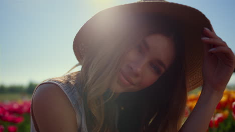 hermoso retrato de mujer quitándose el sombrero de paja a la luz del sol en un fondo floral.