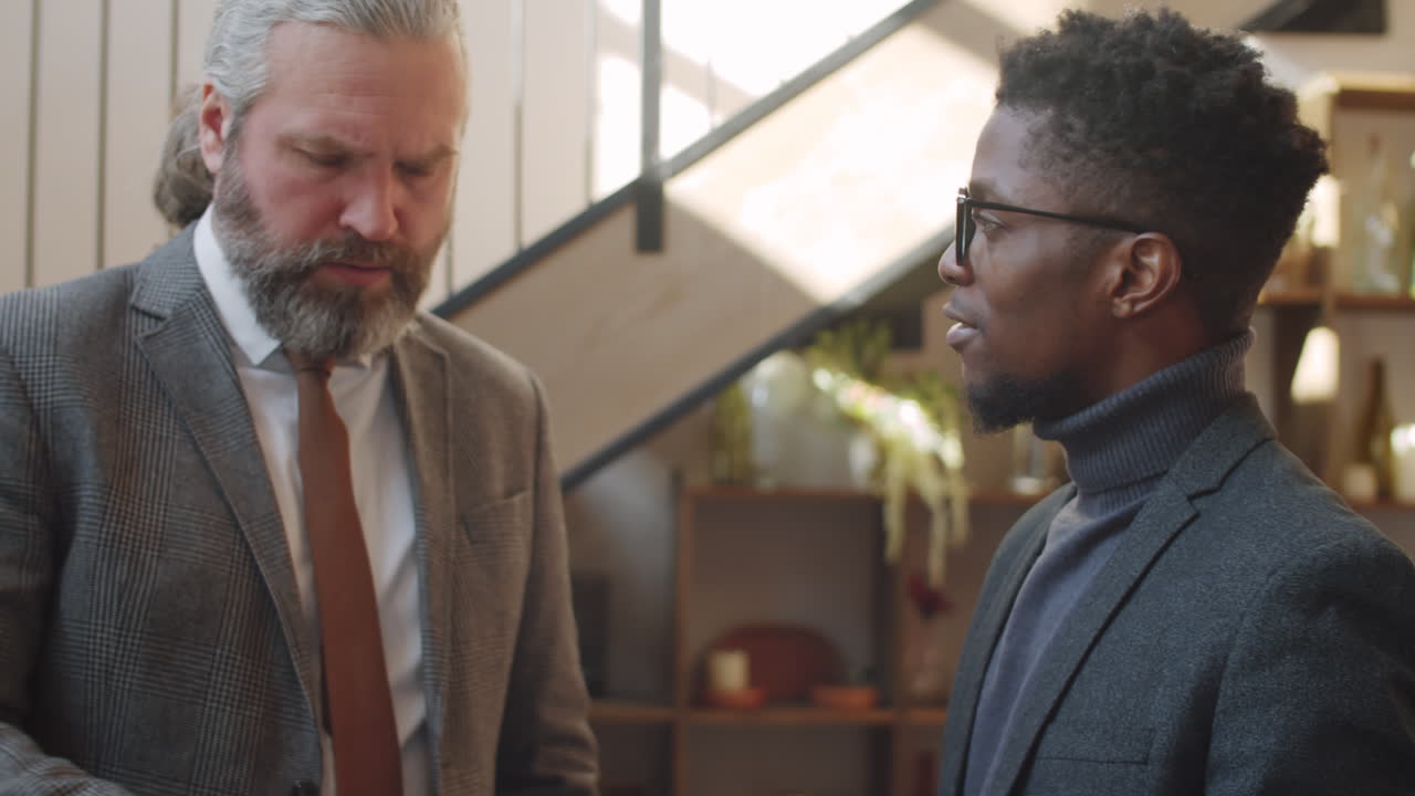Multiethnic Male Colleagues Using Tablet and Talking in Restaurant