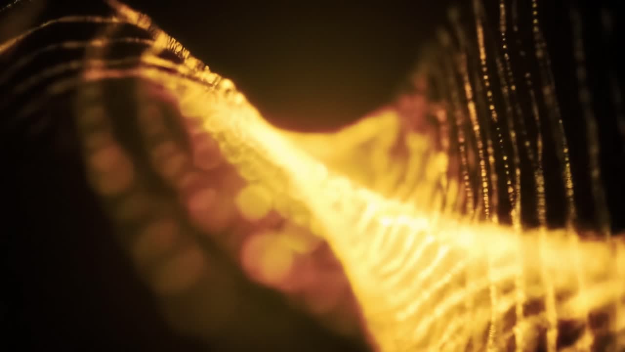 A captivating display of golden wave patterns moves gracefully against a dark background. This artistic visualization creates stunning light effects that engage viewers.
