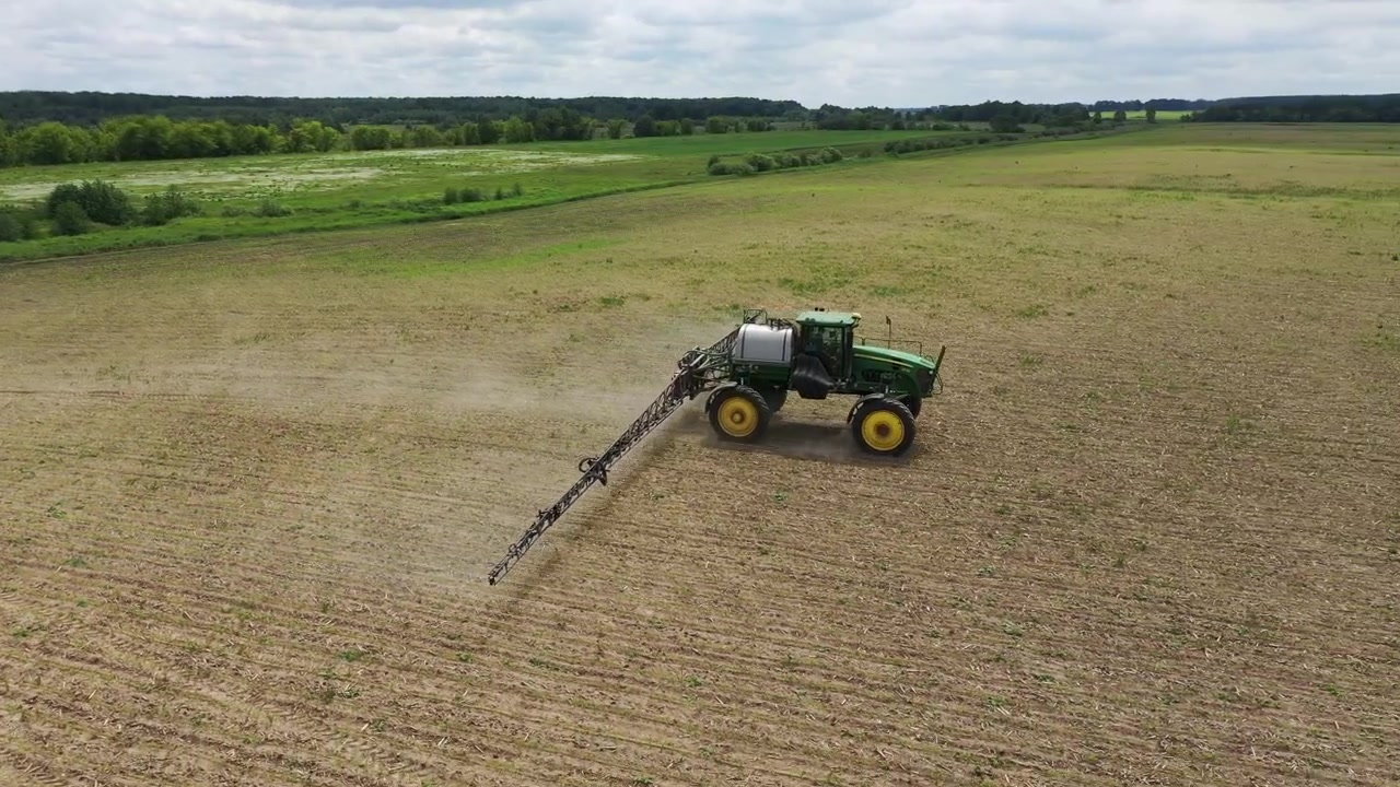 Trattore Agricolo Irroratore al Lavoro in un Grande Campo