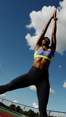 athletic woman stretching outdoors under blue sky