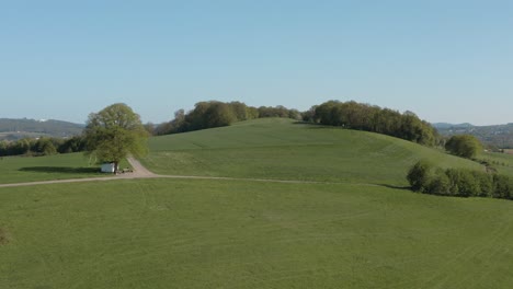 Drone---Aerial-panorama-shot-of-al-lonely-chapel-on-a-field-with-grass-and-a-road-with-panorama-of-the-seven-mountains---Siebengebirge-30p