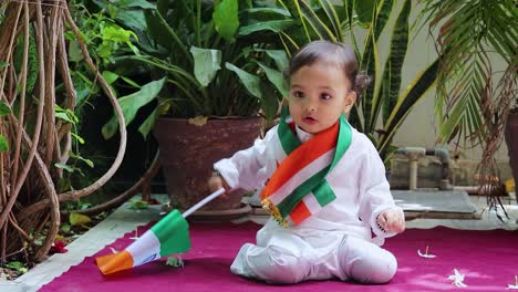 cute toddler waving indian tricolor flag in traditional cloth with innocent facial expression