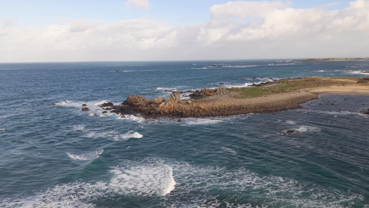 Onde bianche spumeggianti che arrivano a riva nel sole del tardo pomeriggio, avvicinandosi a un promontorio roccioso sotto il sole dorato e vedute sul mare a Guernsey.