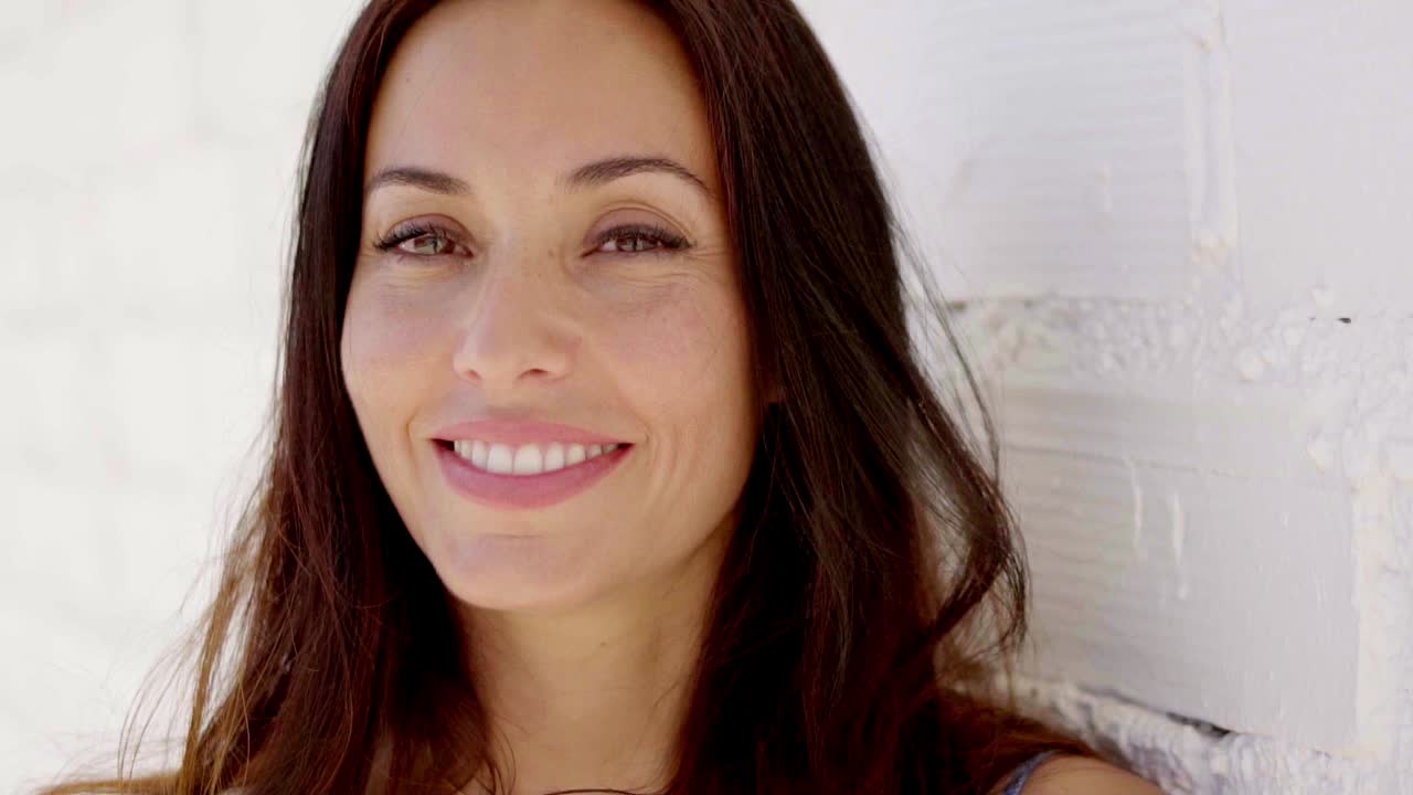 un primer plano de una mujer con el cabello marrón sonriendo