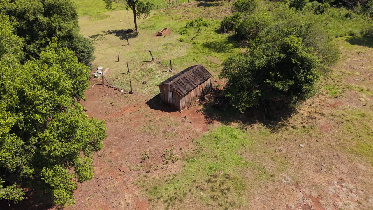 Establisher Aerial view of a Wooden old cabin alone in a rural farm field, green landscape at daylight