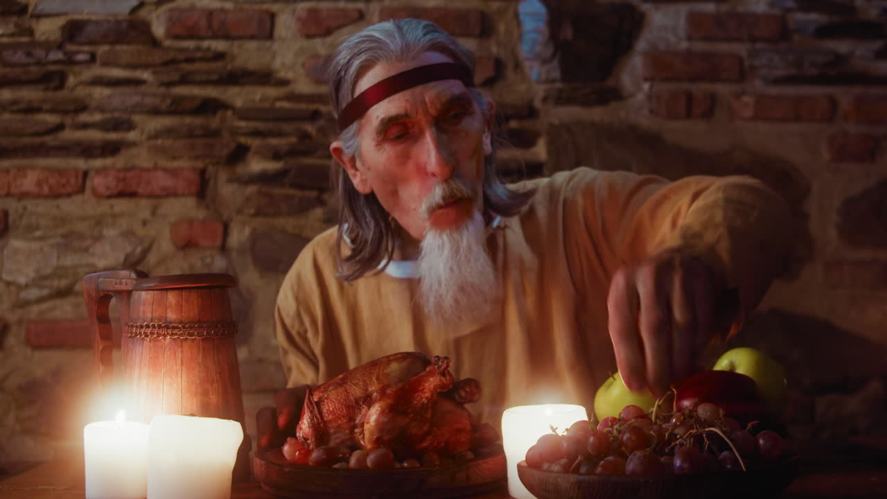 중세 파티에서 의 다리를 어내는 노인, 염소 수염을 가진 회색 머리 귀족, 술집의 식탁에서 구운 고기를 먹는, 숙소 손님을 위해 부유한 보상