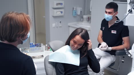 Smiling woman in stomatology clinic. Male dentist talking to a patient while showing jaw model. Modern dental cabinet. Treating teeth.