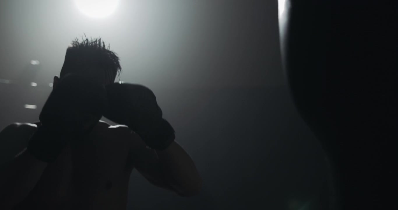 Silhouette of a Boxer Training in a Dark Gym