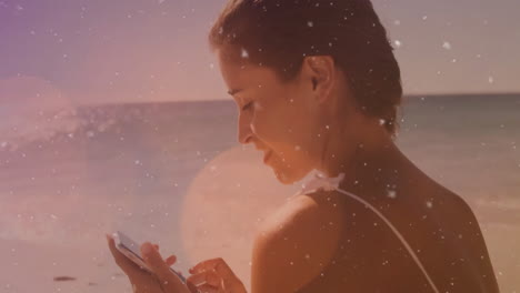 woman using smartphone on beach with sparkling light animation over scene