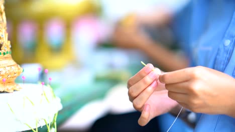 hand holding needle to making garland