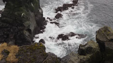 dramático zoom fuera del océano atlántico olas salpicaduras contra el acantilado de roca oscura