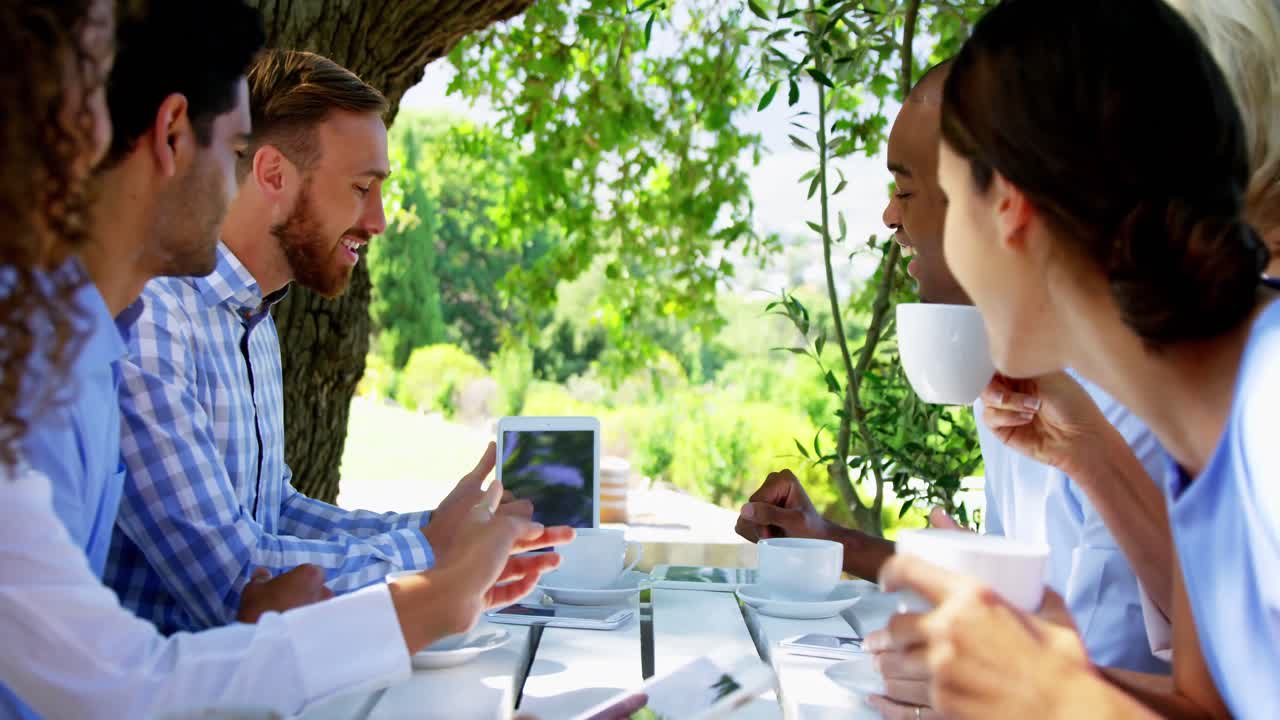 Group of friends discussing over digital tablet at outdoor caf&Atilde;&copy;