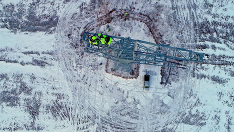 aerial top down shot of worker in neon clothes climbing on top of transmission tower and repairing or installing