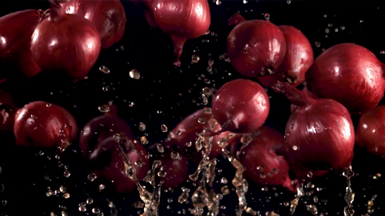 Fresh Red Onions Falling with Water Splashes in Slow Motion