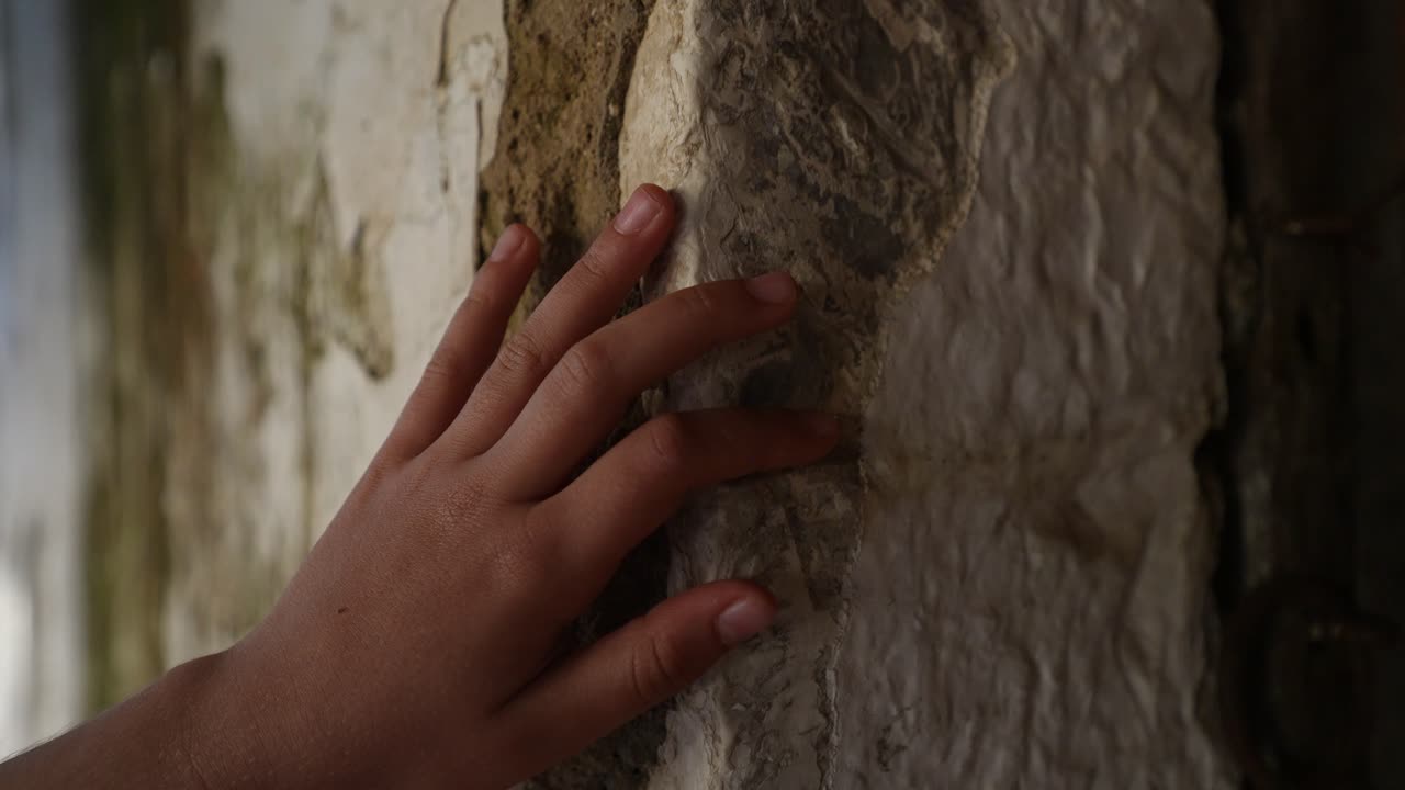 Child Hand Touching Stone Wall of Old House Representing Longing for Tradition and Family Memories