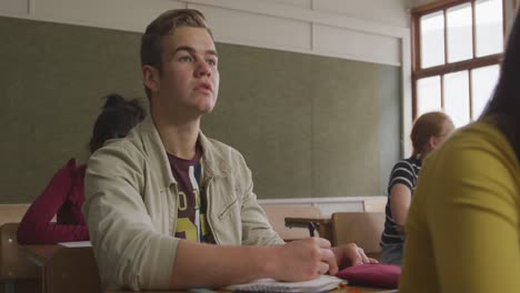niño caucásico levantando la mano en la clase