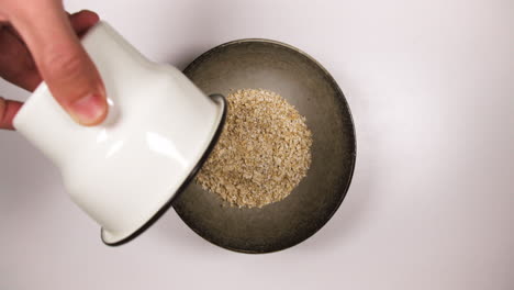 Preparar-Gachas-De-Avena-Para-Un-Desayuno-Saludable-En-La-Mesa---Verter-Avena-Arrollada-Y-Leche-En-Un-Tazón-Y-Luego-Poner-Una-Cuchara-Negra