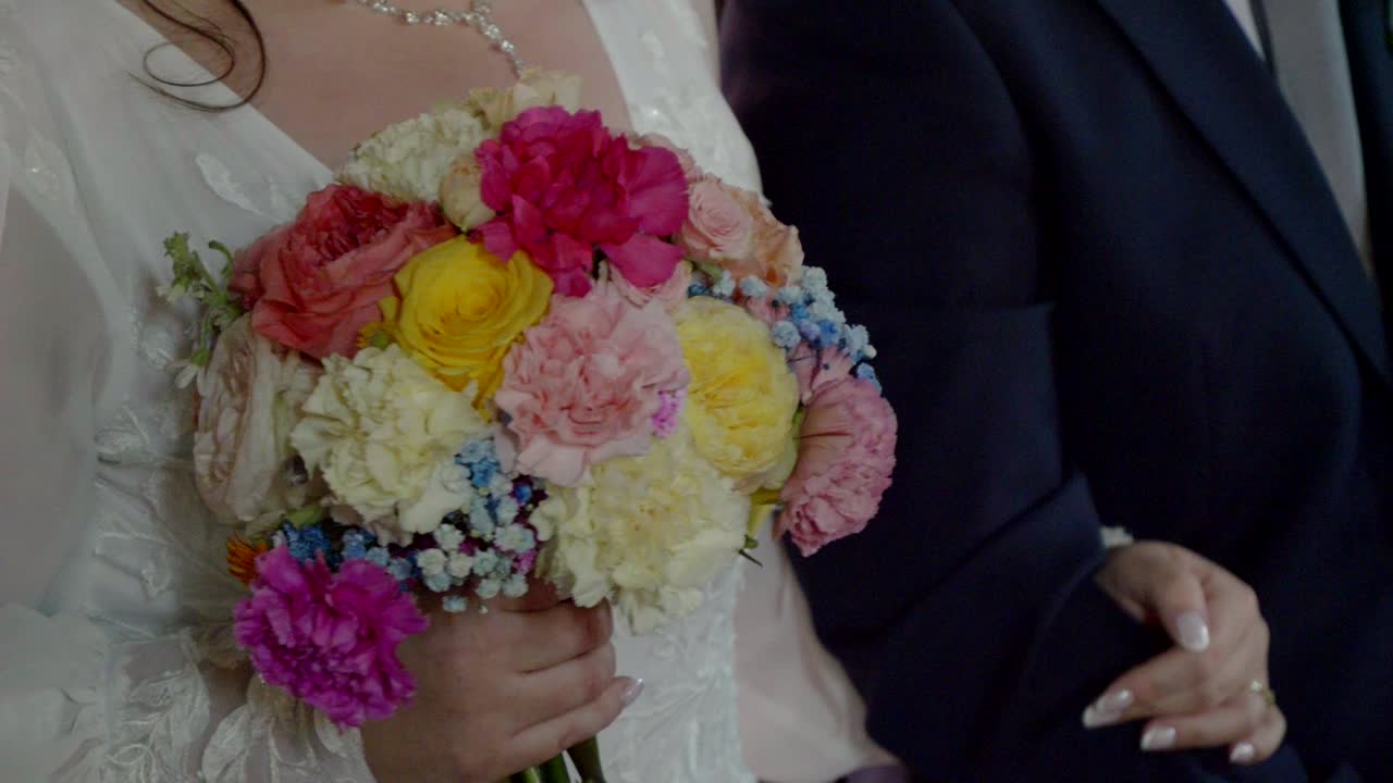Primer plano de novio y novia sujetando un ramo de boda en una iglesia